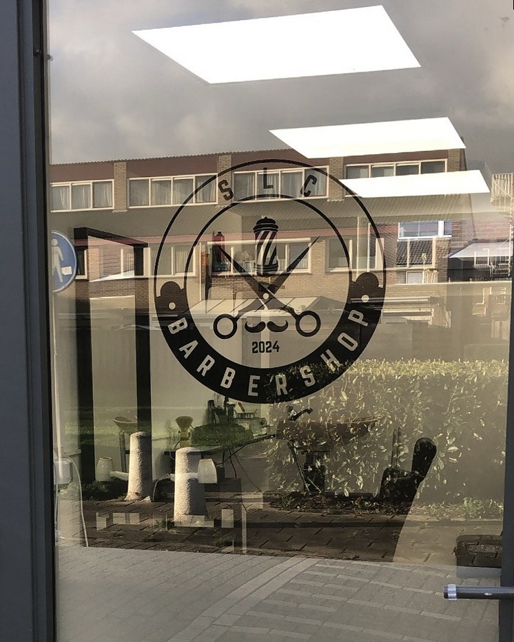 De glazen voordeur van SLC Barbershop met het ronde logo op het glas